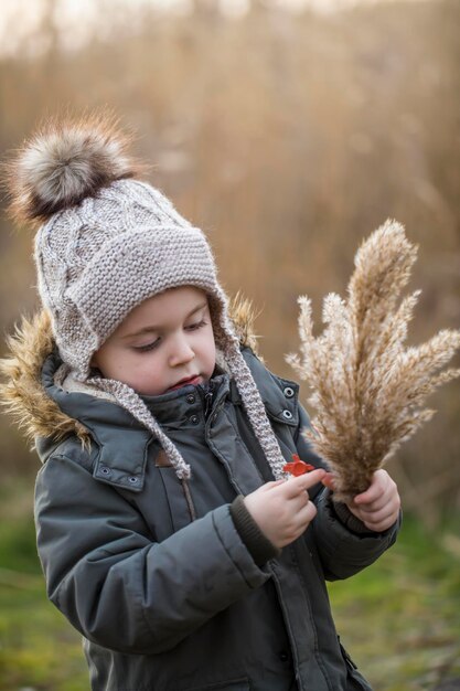 Portret jongen op achtergrond herfst droog gras Pampas gras kind loopt en verzamelt herfst natuurlijke materialen voor ambachten Verticale foto
