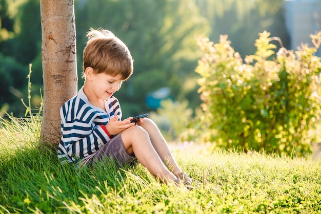 portret jongen zittend op het gras met telefoon