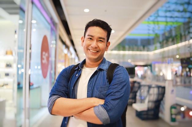 Portret lachende Aziatische man in casual shirt staande in supermarkt