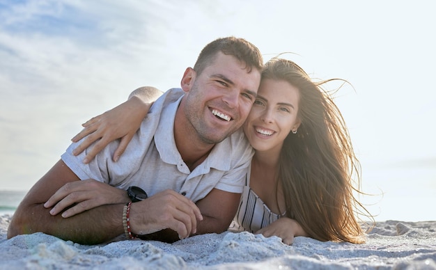 Portret liefde en ontspannen paar strand en vakantie in de zomer zonsondergang Gelukkige vrouw knuffel haar vrolijke man liggend in het zand aan de kust op vakantie of vriend en vriendin genieten van reizen over de oceaan