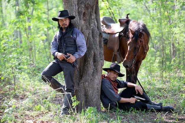 portret man met hoed staande door boom met paard als cowboy