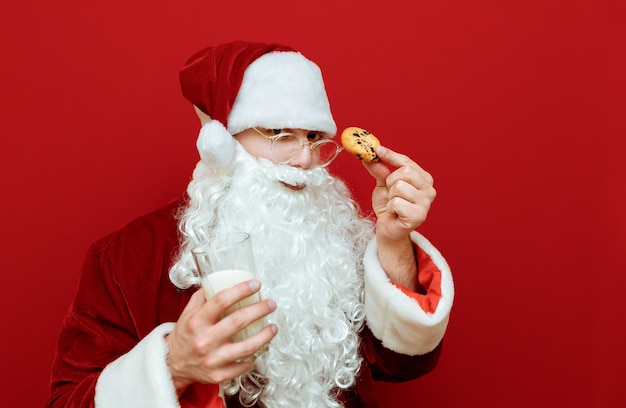 Portret man verkleed als kerstman met glas melk en plaat met chocoladekoekjes