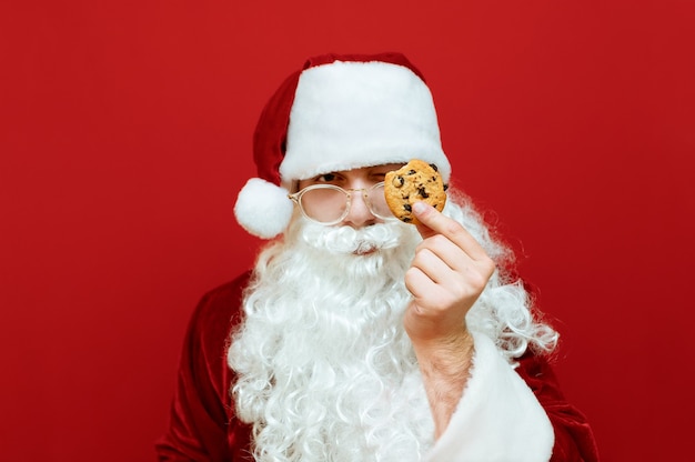 Portret man verkleed als kerstman met glas melk en plaat met chocoladekoekjes