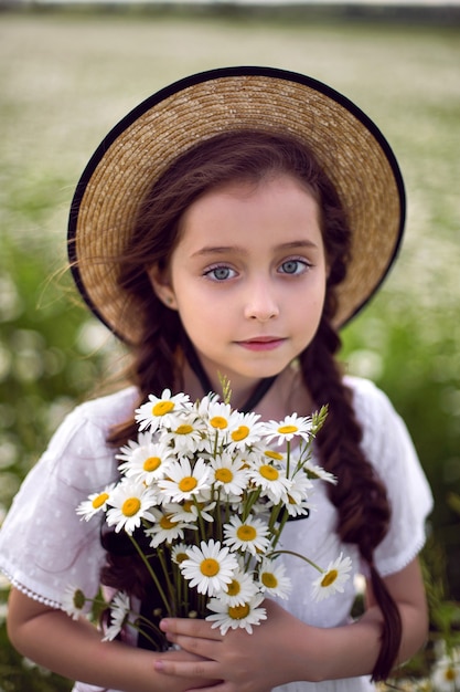 Portret meisje in een witte jurk met hoed op bloemen veld