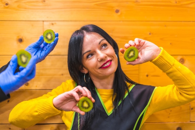 Foto portret met veel kiwi's in de hand van een brunette kaukasisch fruitmeisje