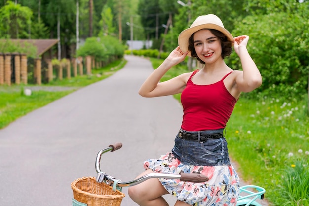 Portret mooi jong meisje in hoed met fiets op straat op het platteland