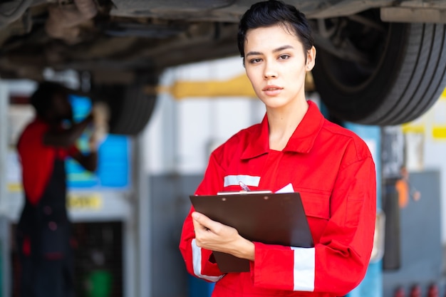 Portret Mooie blanke vrouwelijke monteur draagt rode uniform en checklist