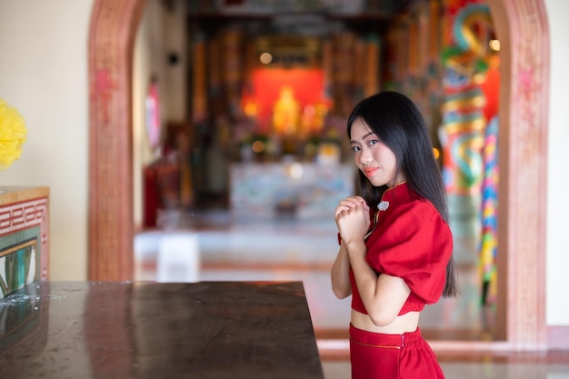 Portret mooie glimlach Aziatische jonge vrouw dragen rode cheongsam jurk traditionele decoratie voor Chinees Nieuwjaar festival vieren cultuur van China bij Chinese heiligdom Openbare plaatsen in Thailand