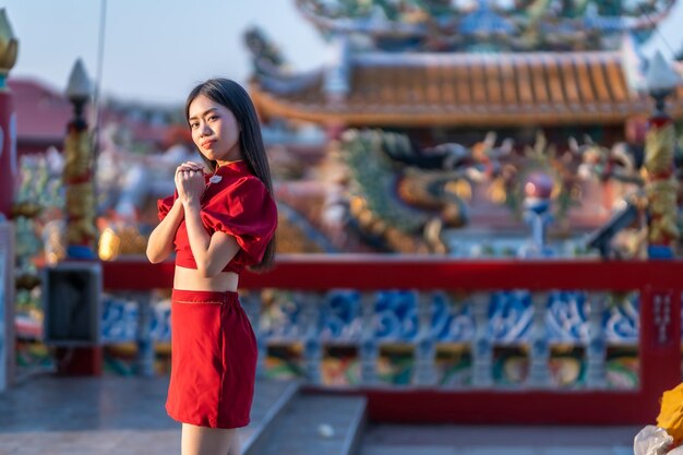 Portret mooie glimlach Aziatische jonge vrouw dragen rode cheongsam jurk traditionele decoratie voor Chinees Nieuwjaar festival vieren cultuur van China bij Chinese heiligdom Openbare plaatsen in Thailand