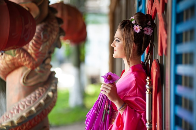 Portret mooie glimlach Aziatische jonge vrouw, gekleed in rode traditionele Chinese cheongsam decoratie