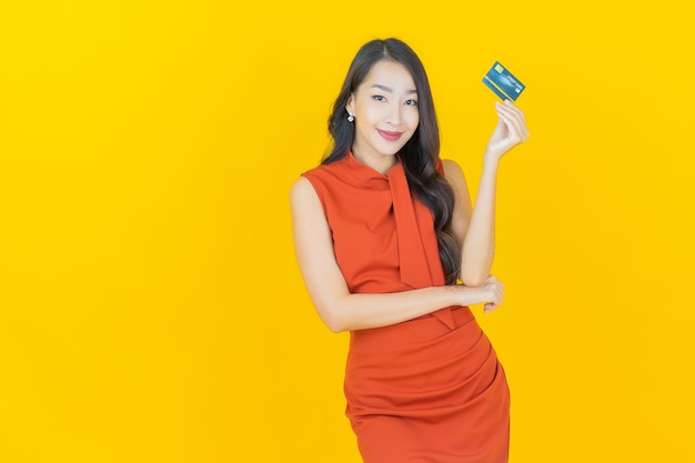 Portret mooie jonge Aziatische vrouw glimlach met creditcard op geel