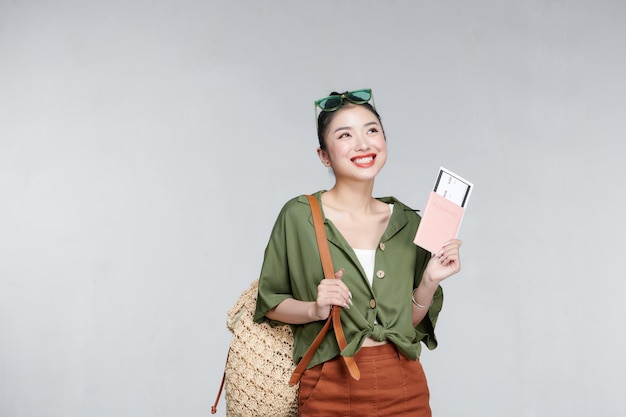 Portret mooie jonge aziatische vrouw met rugzak reistas met paspoort en boarding pass ticket op grijze achtergrond