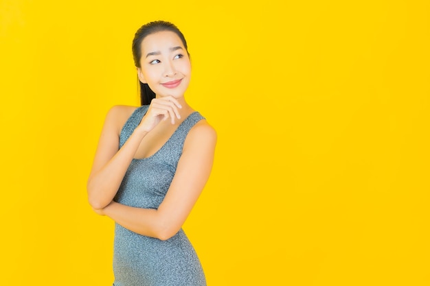 Portret mooie jonge Aziatische vrouw met sportkleding klaar voor oefening op gele muur