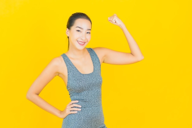 Portret mooie jonge Aziatische vrouw met sportkleding klaar voor oefening op gele muur