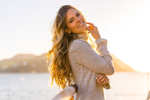 Portret mooie jonge vrouw aan de kust bij zonsondergang