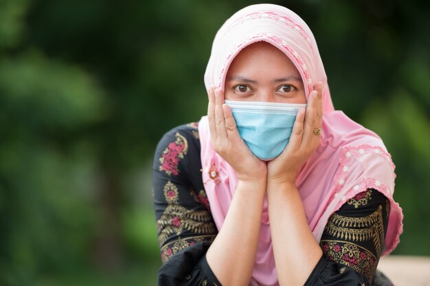 Portret moslimvrouw met masker, kijk naar de camera met plezier