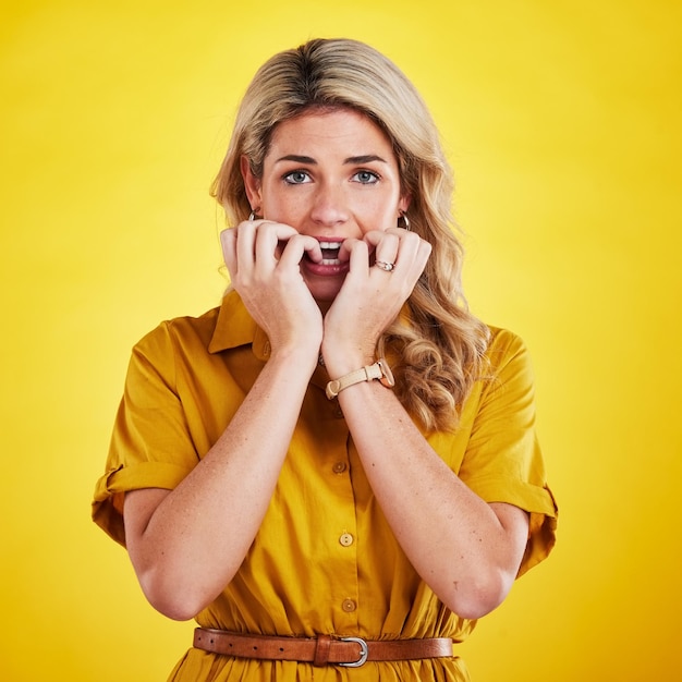 Portret nagels bijten en vrouw in studio met angst nerveus en bang tegen gele achtergrond Paniek angst en gezicht van dame met slechte gewoonte fobie en stress bang en bezorgd over fouten