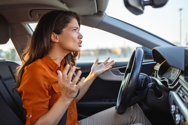 Portret ontevreden boos pissig agressieve vrouw rijdende auto schreeuwen tegen iemand in het verkeer hand vuist omhoog in lucht voorruit weergave Emotionele intelligentie concept Negatieve menselijke expressie