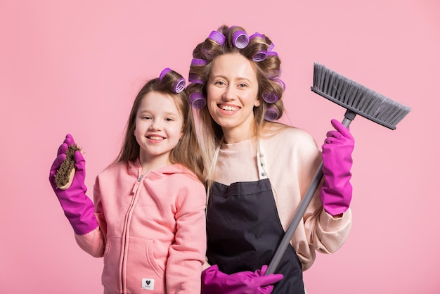 Portret op een roze achtergrond van moeder met dochter die het appartement schoonmaakt