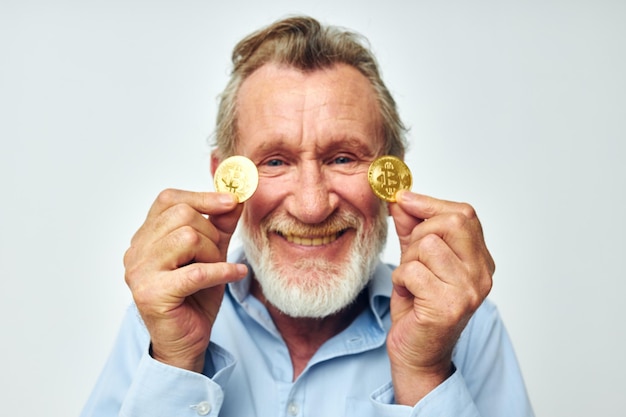 Portret oudere man in een blauw shirt bitcoins op de lichte achtergrond van het gezicht