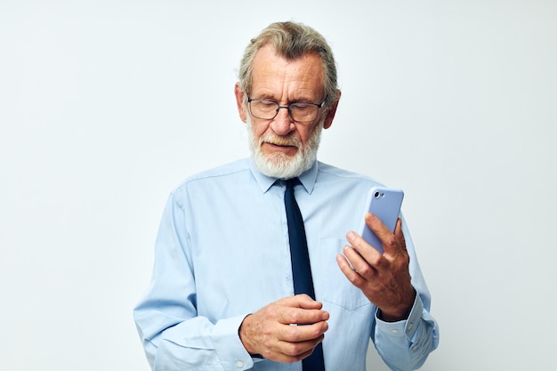 Portret oudere man in een overhemd met een stropdas praten aan de telefoon lichte achtergrond