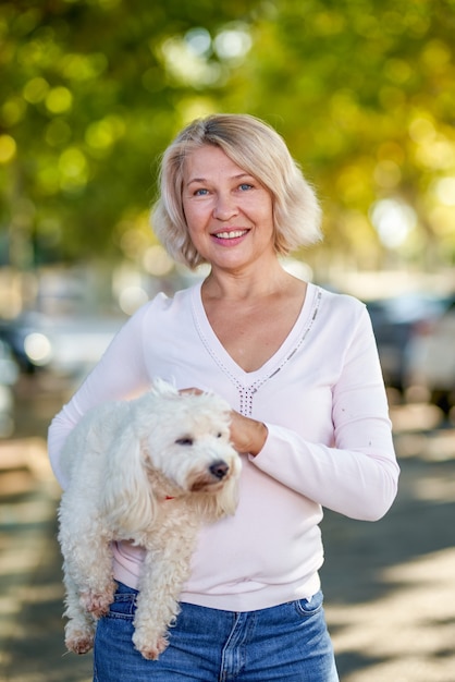 Portret oudere vrouw met een hond buitenshuis.