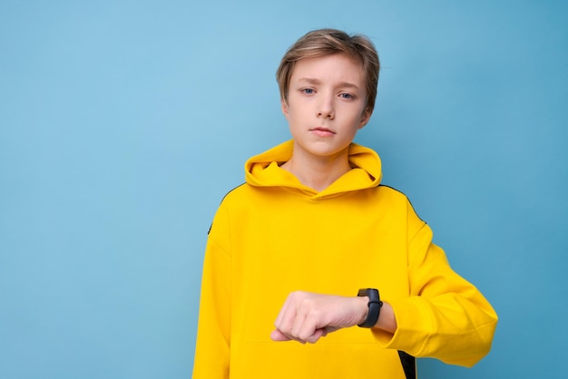 Portret peinzende vrolijke jonge kerel kijken naar fitness armband kopie lege advertentieruimte geïsoleerd op blauw...