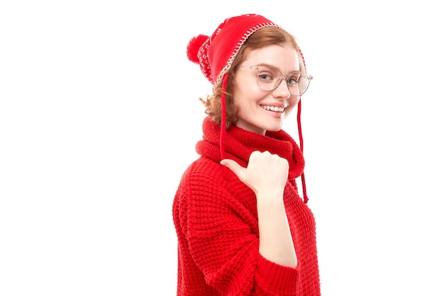 Portret positieve roodharige jonge vrouw in rode kerst trui glimlachend wijzende vinger naar lege kopie ruimte voor tekst of product geïsoleerd op een witte achtergrond reclamebanner