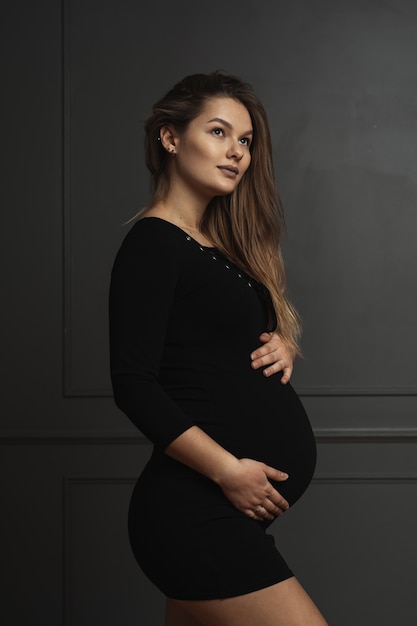 Portret prachtige jonge zwangere vrouw zachtjes aanraken met de hand