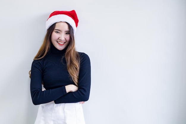 Portret schattige Aziatische jonge vrouw in kostuum Kerstmis en draag rode kerstman hoed met glimlach op witte achtergrond en kopieer ruimte. Gelukkig van tiener vrouw in thema Kerstmis.
