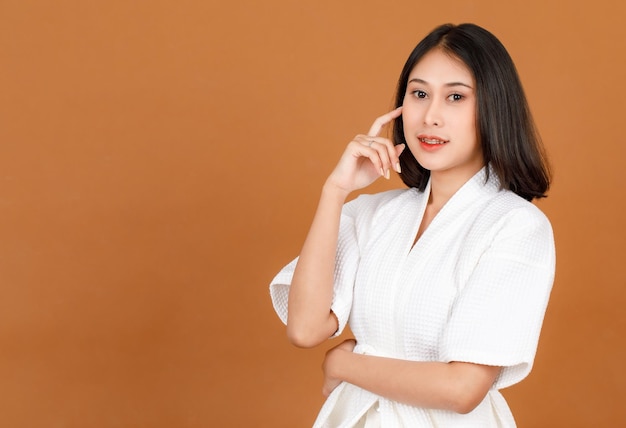 Portret schoonheid shot van millennial jong aziatisch vrouwelijk model in douche touw staande glimlachende blik op camera gekruiste arm met hand vinger omhoog in de buurt van gezicht denken idee op bruine achtergrond.