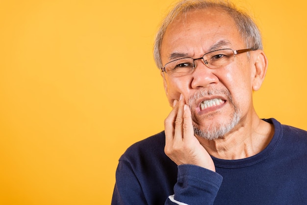 Portret senior oude man trieste hand wat betreft wang die lijdt aan kiespijn