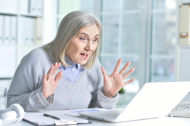 Portret senior vrouw met behulp van laptop in office