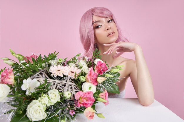 Portret sexy jonge vrouw met roze haar, mooie boeket bloemen in de hand.