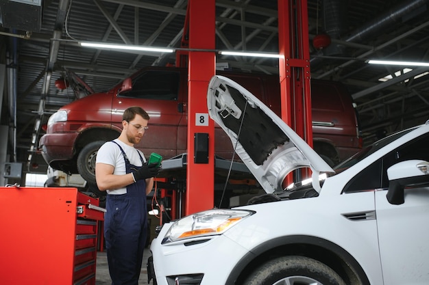 Portret shot van een knappe monteur die aan een voertuig werkt in een moderne schone werkplaats voor autoservice