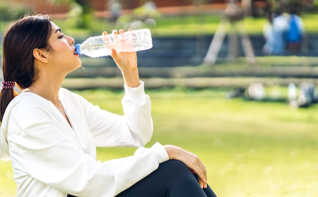 Portret sport aziatische schoonheid lichaam slanke vrouw drinkwater uit een fles terwijl u ontspant en zich fris voelt op groene natuurlijke achtergrond in zomer groen park gezonde levensstijl concept