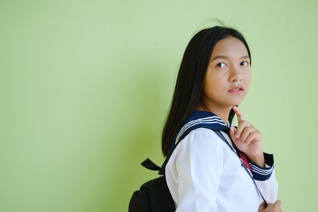 Portret student jong meisje in uniforme school en rugzak op groene achtergrond, Aziatisch meisje, tiener.