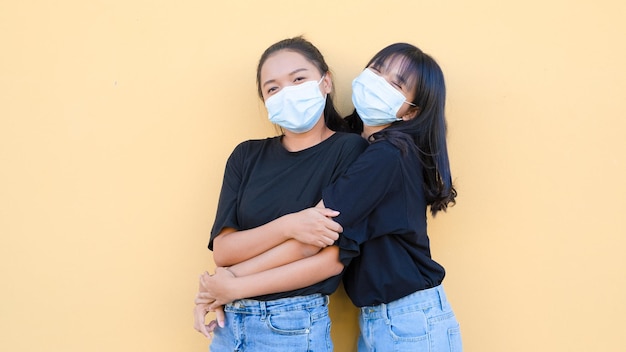 Portret twee jonge meisjes dragen een masker dat samen staat op oranje backgroynd