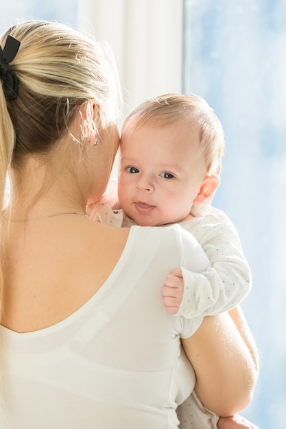 Portret van 3 maanden oude babyjongen die moeder knuffelt