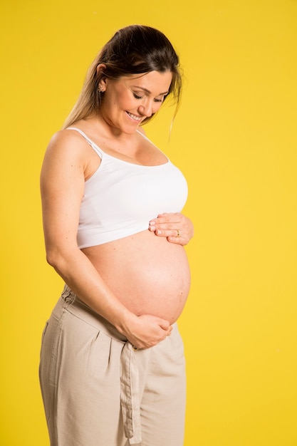 Portret van 9 maanden zwangere vrouw over gele muur