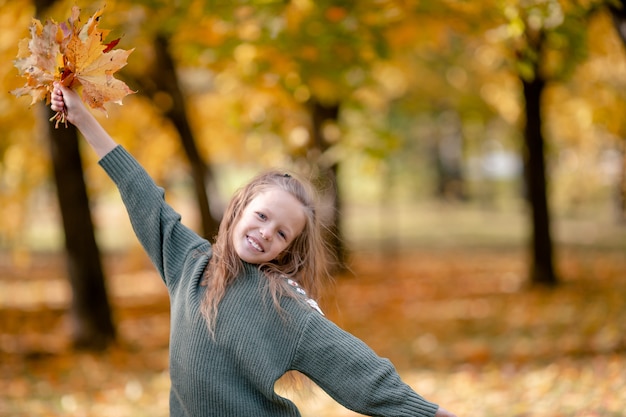 Portret van aanbiddelijk meisje met geel bladerenboeket in herfst