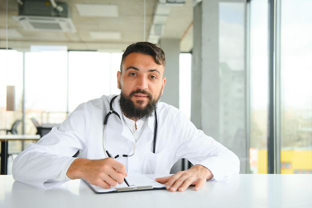Portret van aangename jonge Arabische dokter in witte jas