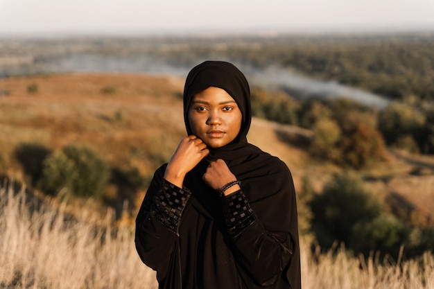 Portret van aantrekkelijk Afrikaans meisje in zwarte traditionele robe. Salah bidden in god.