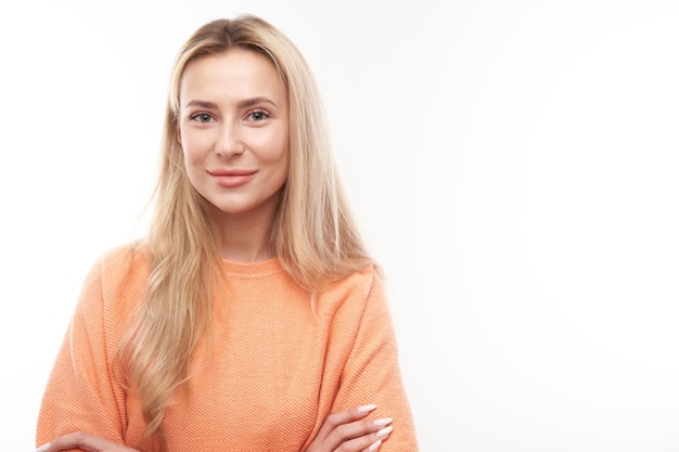 Portret van aantrekkelijk blond meisje in oranje casual poseren en lachend vreugdevol geïsoleerd op witte studio achtergrond