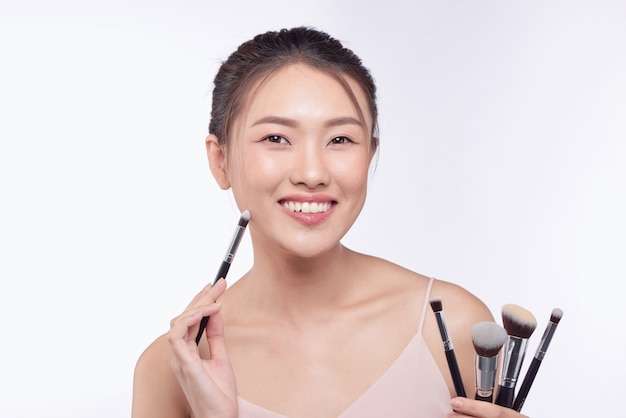 Portret van aantrekkelijke aziatische lachende vrouw brunette met borstels voor make-up
