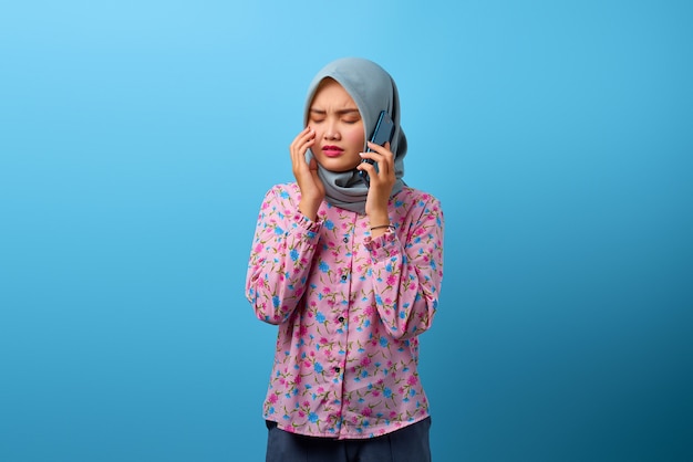 Portret van aantrekkelijke Aziatische vrouw die op smartphone praat en huilend kijkt