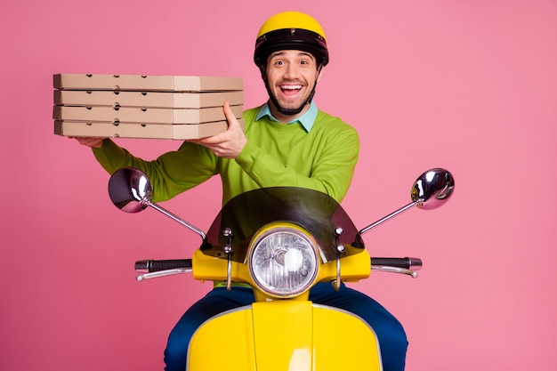 Portret van aantrekkelijke blije kerel die het leveren van hete smakelijke pizza berijdende motorfiets vervoert