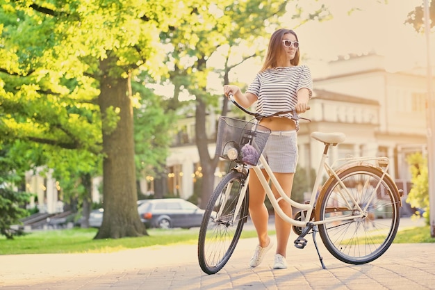 Portret van aantrekkelijke brunette vrouw met stadsfiets in een zomer buiten park.