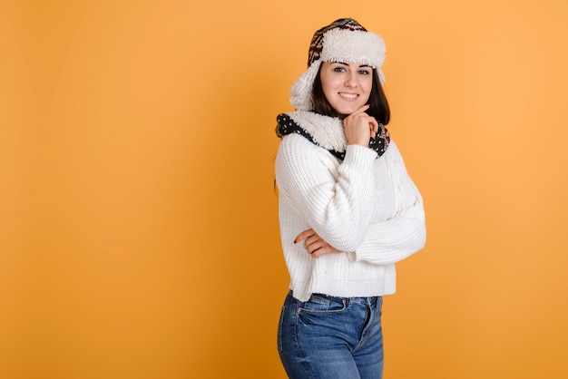 Portret van aantrekkelijke die vrouw in bonthoed op oranje achtergrond wordt geïsoleerd