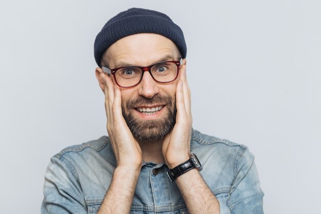 Portret van aantrekkelijke jonge man met dikke baard en snor kijkt met opgetogen uitdrukking